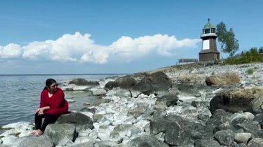 Deniz kıyısında dinlenen Asyalı bir kadın. Huzur anlarında bulunan ruh sağlığı ve kendine güvenin ilham kaynağı. Kadınlar boş vakitlerini doğada geçirirler.. 