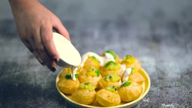 Baharatlı suyla kaplı bir tabak bardakta Hint sokak yemeği fuşkası yakın. Dahi Pani puri Hindistan 'da bir sohbet konusu. 4K Hint sokak yemekleri.