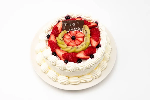 Homemade birthday cake decorated with strawberries, kiwi fruit and blueberries isolated on white background in top view.