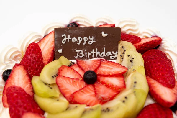 Homemade birthday cake decorated with strawberries, kiwi fruit and blueberries isolated on white background in side view and closeup. Copy space.