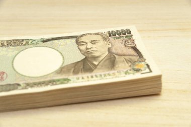 10 bin yen (10 bin yen) banknotlar istiflendi. Japon parası. Kağıt para. Tahta masada izole edilmiş. Yan görünüm.