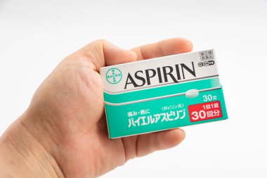 Fuji City, Shizuoka Prefecture, Japan - April 23, 2024: Hand holding Aspirin 30 tablets by Bayer Global isolated on white background. clipart