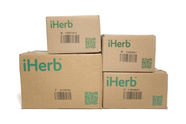 Fuji-shi, Shizuoka-ken, Japonya - 28 Eylül 2024: iHerb, çevrimiçi destek ve vitamin deposu - beyaz arka planda izole edilmiş karton paketleme kutuları.
