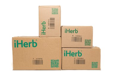 Fuji-shi, Shizuoka-ken, Japonya - 28 Eylül 2024: iHerb, çevrimiçi destek ve vitamin deposu - beyaz arka planda izole edilmiş karton paketleme kutuları.