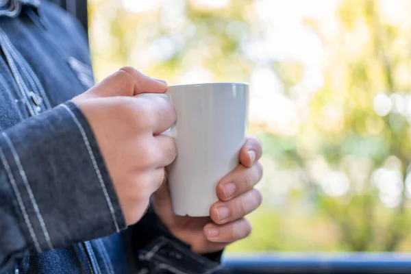 男人的手捧着一杯咖啡 放在窗外 窗外是秋天的背景 — 图库照片