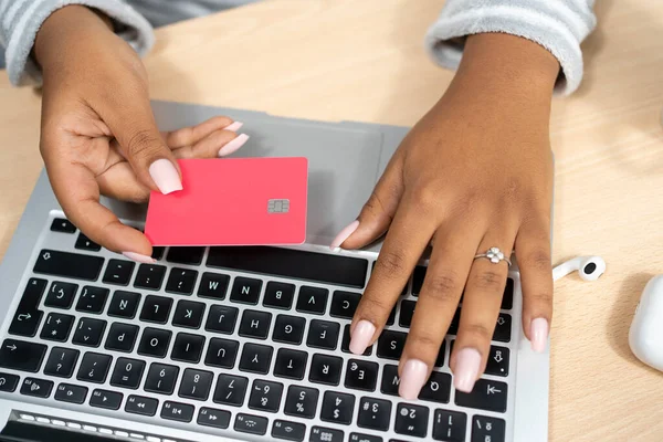 アフリカ系アメリカ人女性は 支払いのためのクレジットカードでオンラインでノートパソコンの画面ショッピングを見る — ストック写真