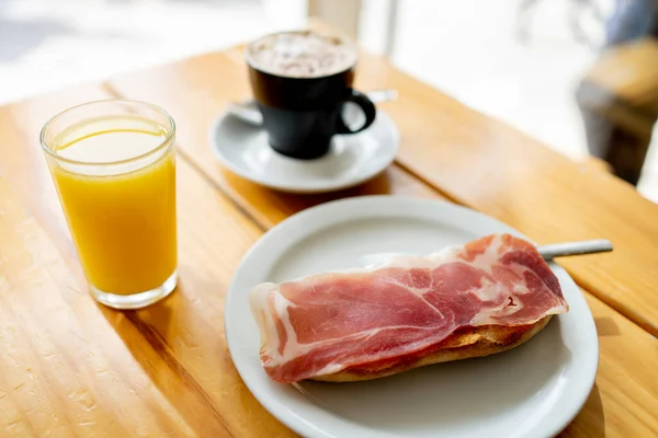 a typical Spanish breakfast, coffee with orange juice and toast with Iberian ham, in a cafeteria.