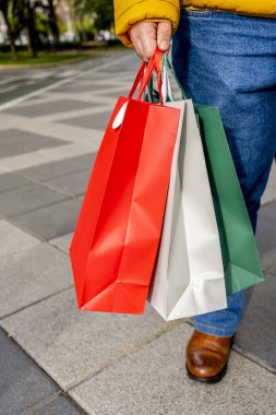 Şehir caddesinde elinde birkaç alışveriş çantası tutan bir adam.