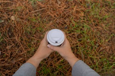 Bir kadının elinde bir fincan kahve tutarken çekilmiş yakın plan fotoğrafı.