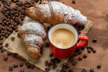 Beyaz kahve fincanı, ahşap masa zemininde kruvasan, seçici odaklanma. Kahvaltı konsepti