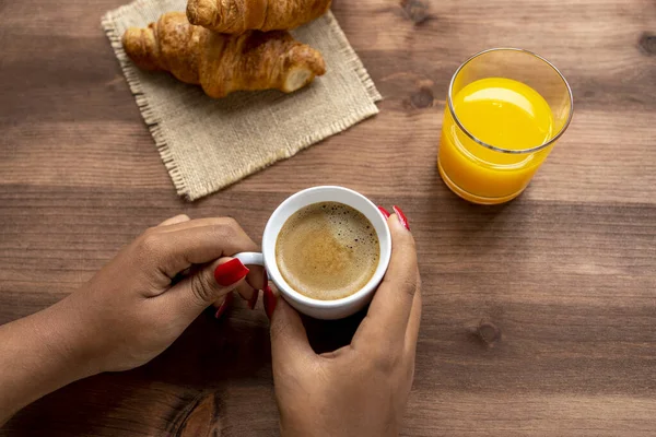 女性の手はオレンジジュースと2人のクロワッサンと素朴な木製のテーブルの上にホットコーヒーのカップを保持 — ストック写真