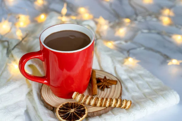 red mug with hot chocolate and Christmas decoration with lights in the background
