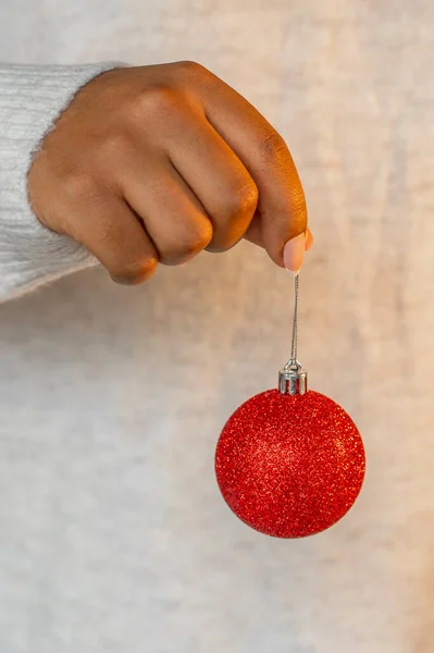 アフリカ系アメリカ人女性の手はクリスマスツリーに赤いボールの飾りを保持します — ストック写真