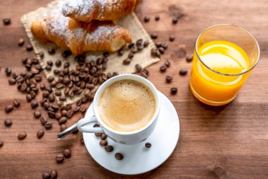 kahve, portakal suyu ve kruvasan kahve çekirdekleri ile süslenmiş ahşap bir masa..