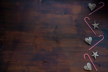 Kırsal Noel süsleri yıldız şeklinde ve siyah ahşap arka planda şeker kamışları olan bir kalp Noel arkaplanı