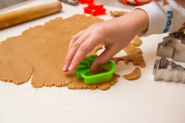 Çocuk hamurdan Noel kurabiyesi kesiyor.