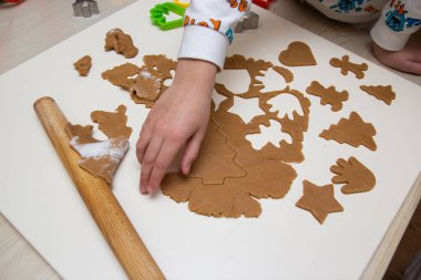 Çocuk hamurdan Noel kurabiyesi kesiyor.
