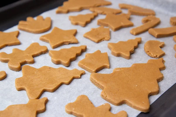 stock image christmas gingerbread on a white parchment on a baking sheet