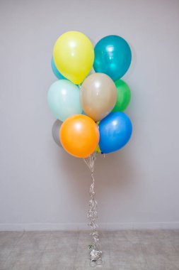 Gri arka planında helyum bulunan renkli balonlar.