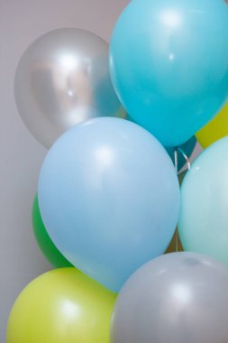 Gri arka planında helyum bulunan renkli balonlar.
