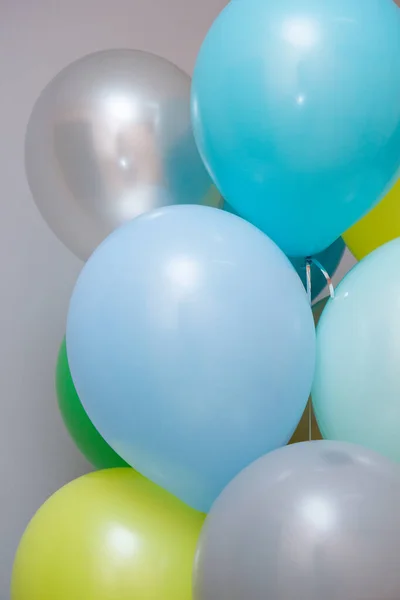 set of colorful balloons with helium on a gray wall background
