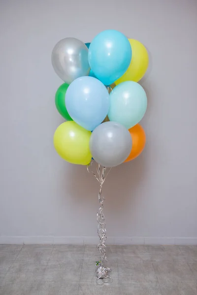 set of colorful balloons with helium on a gray wall background
