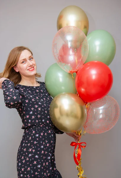 girl with red lipstick with a bunch of balloons against a gray wall