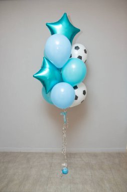 Duvarın arkasında turkuaz ve mavi balonlar, futbol topu şeklinde bir lateks balon.