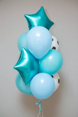 Duvarın arkasında turkuaz ve mavi balonlar, futbol topu şeklinde bir lateks balon.