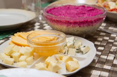 Tabakta peynir dilimleri ve pancar kürkünün altında ringa salatası.