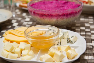 Tabakta peynir dilimleri ve pancar kürkünün altında ringa salatası.