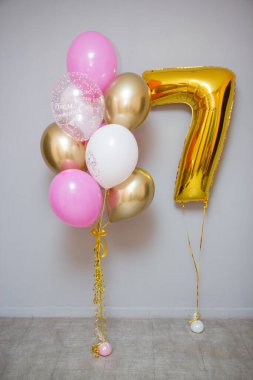 Gri arka planda pembe balonlar ve folyo sarısı 7 numara.