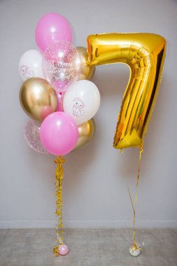 Gri arka planda pembe balonlar ve folyo sarısı 7 numara.