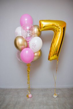 Gri arka planda pembe balonlar ve folyo sarısı 7 numara.