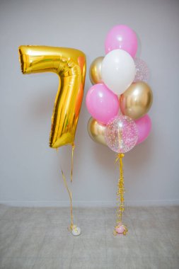 Gri arka planda pembe balonlar ve folyo sarısı 7 numara.