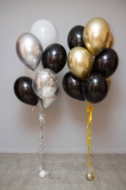 silver, gold, black and white balloons on the floor