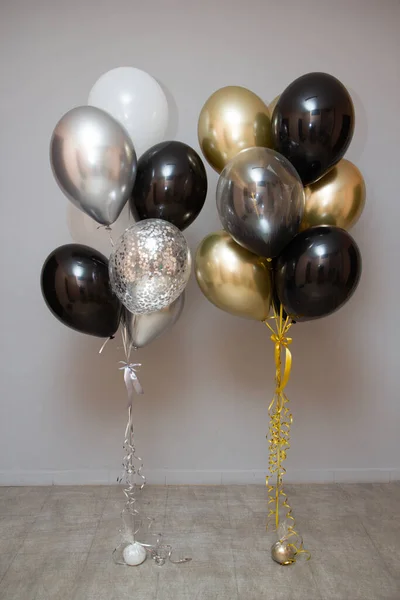 silver, gold, black and white balloons on the floor
