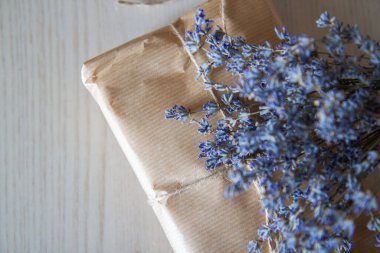 Masanın üzerinde bir demet lavanta olan el işi kağıdından bir hediye.