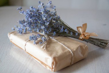 Masanın üzerinde bir demet lavanta olan el işi kağıdından bir hediye.