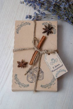 Kahverengi doğum günü hediyesi kutusunda tarçın çubuğu ve bir demet lavanta var.