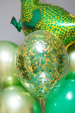 Yeşil dinozor balonu, yeşil balon demeti ve altın konfeti balonları.