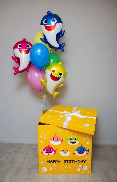 a big yellow box with balloons, a set of balloons baby sharks