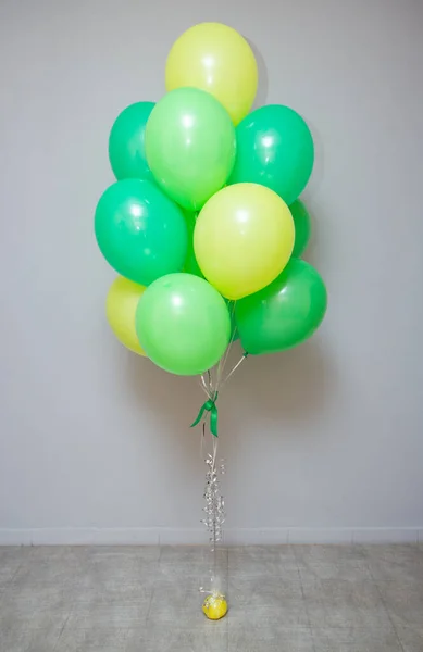 a bunch of green and light green balloons with helium on a white background, birthday