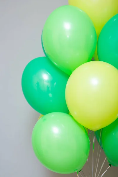 a bunch of green and light green balloons with helium on a white background, birthday