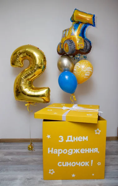 A yellow box with balloons, a gold balloon number 2, a foil tractor balloon, the inscription on the balloon Happy Birthday, the inscription on the box: Happy Birthday, son! Balloons for a boy for a holiday on a white background