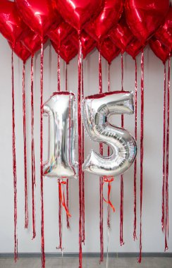 Kırmızı kalplerin arka planında 15 numaralı gümüş balonlar.