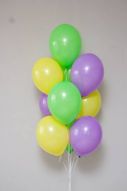 Beyaz arka planda sarı ve mor helyum balonları.