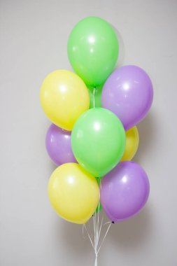 Beyaz arka planda sarı ve mor helyum balonları.