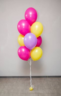 Beyaz arka planda bir grup sarı ve pembe helyum balonu
