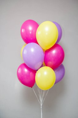 Beyaz arka planda bir grup sarı ve pembe helyum balonu